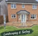 Brick house with a new front lawn, a path to a white porch, and planting by the door.